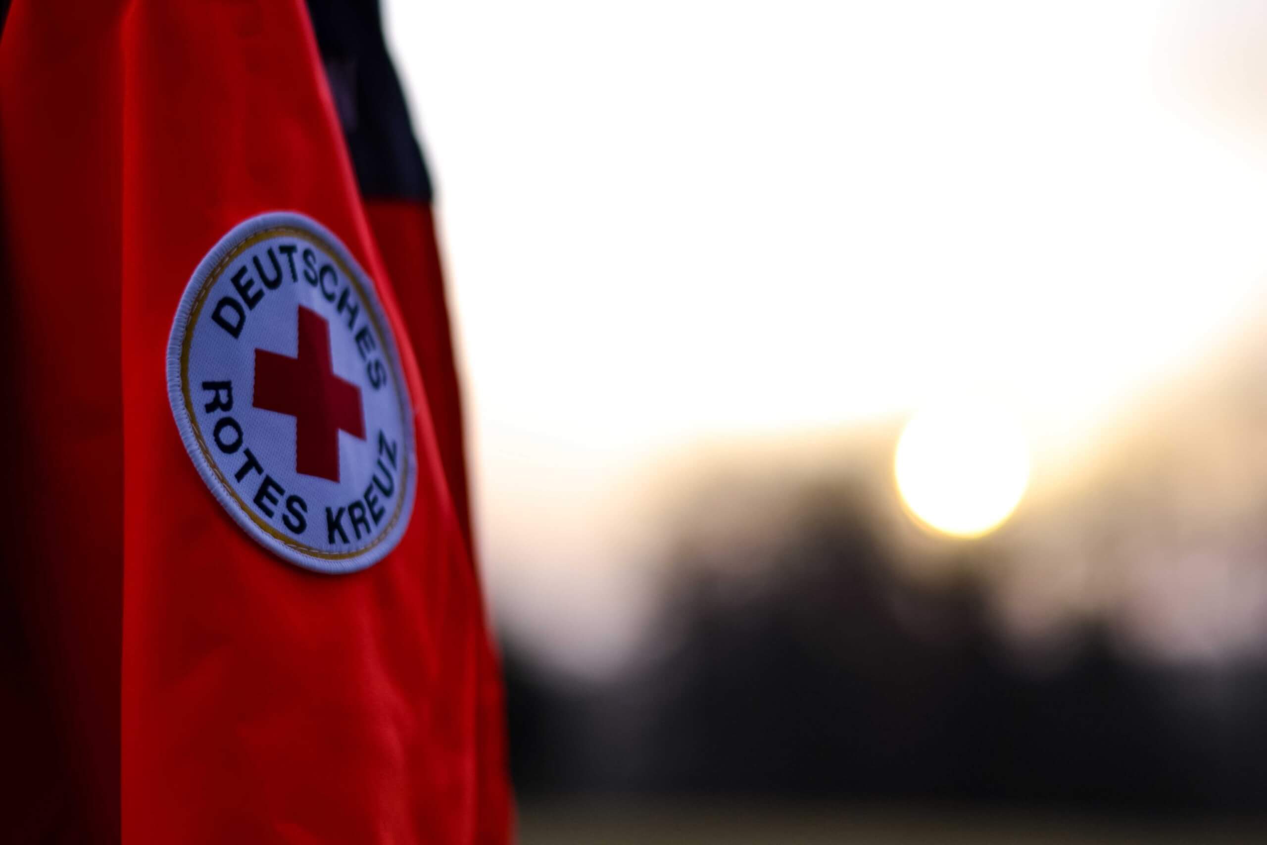 Orange Jacke mit der Aufschrift Deutsches Rotes Kreuz vor einem Sonnenuntergang.