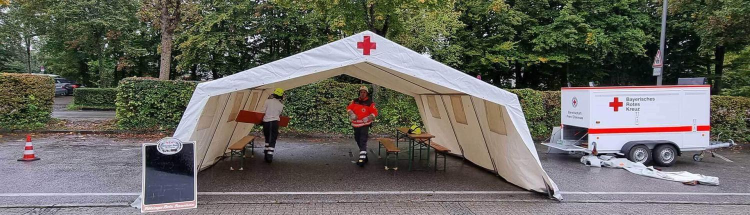 Mitglieder der BRK Bereitschaft Prien bauen ein Zelt neben ihrem Anhänger auf.